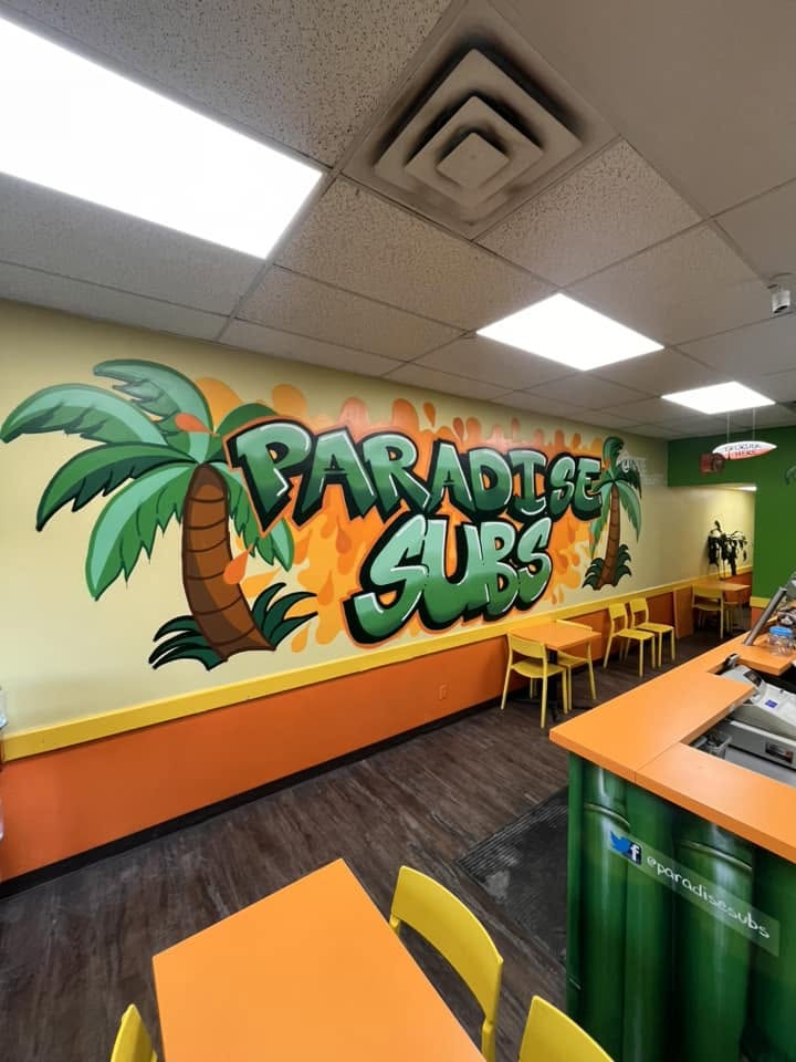 Hand-painted Paradise Subs mural with a cartoon palm tree on the dining room wall